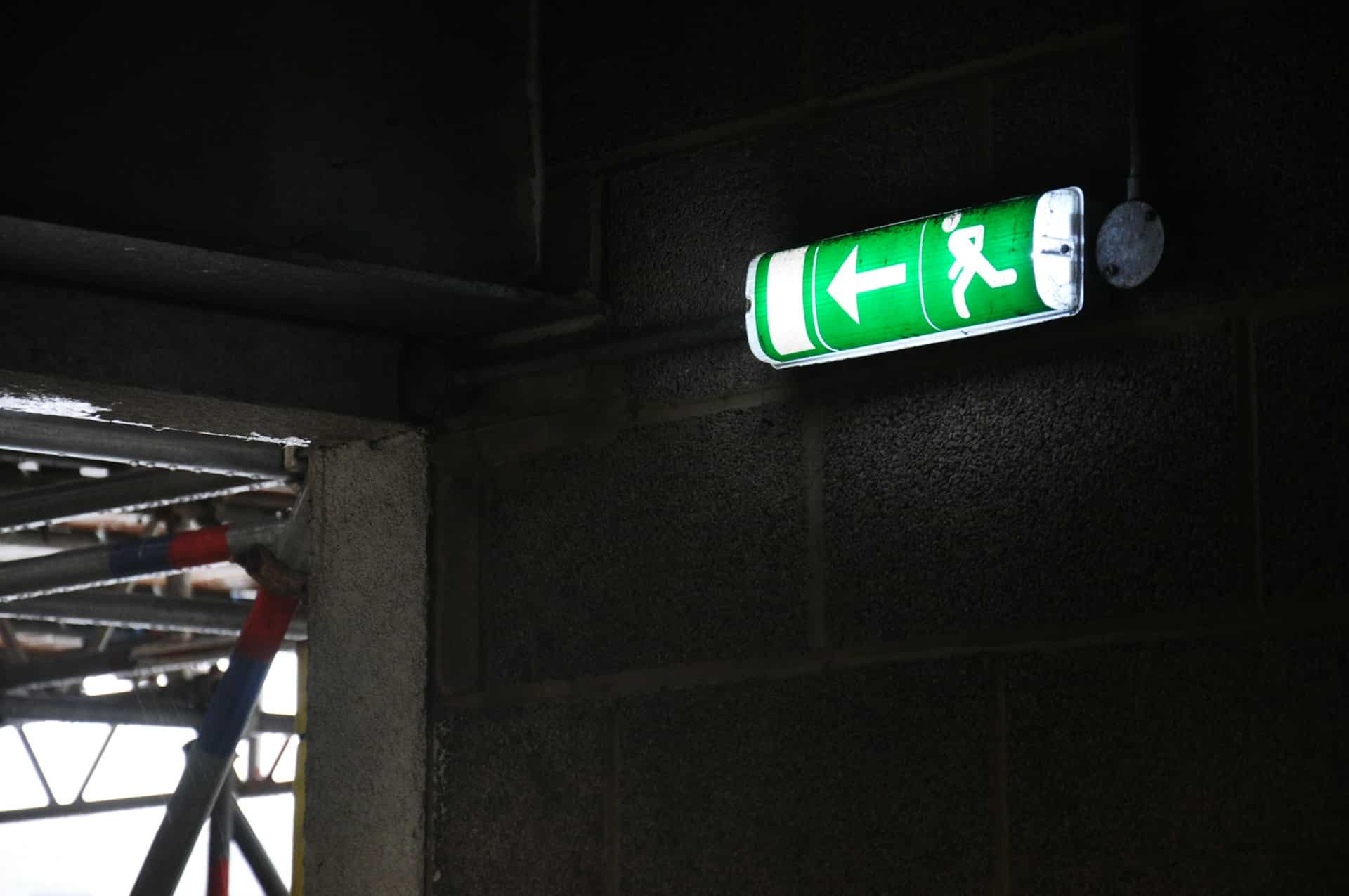 A fire exit sign illuminating the hallway of a property.